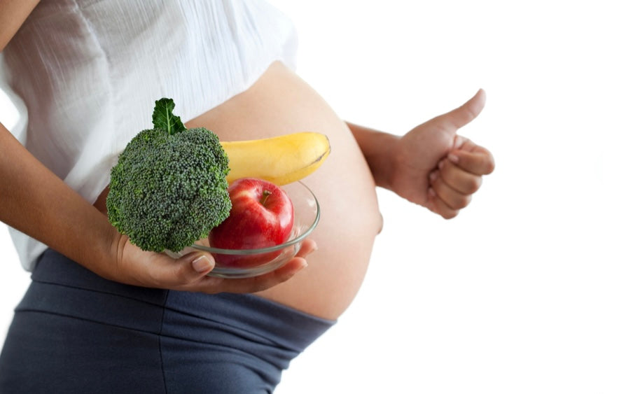 Pregnant woman holding bowl of fruit and veggies